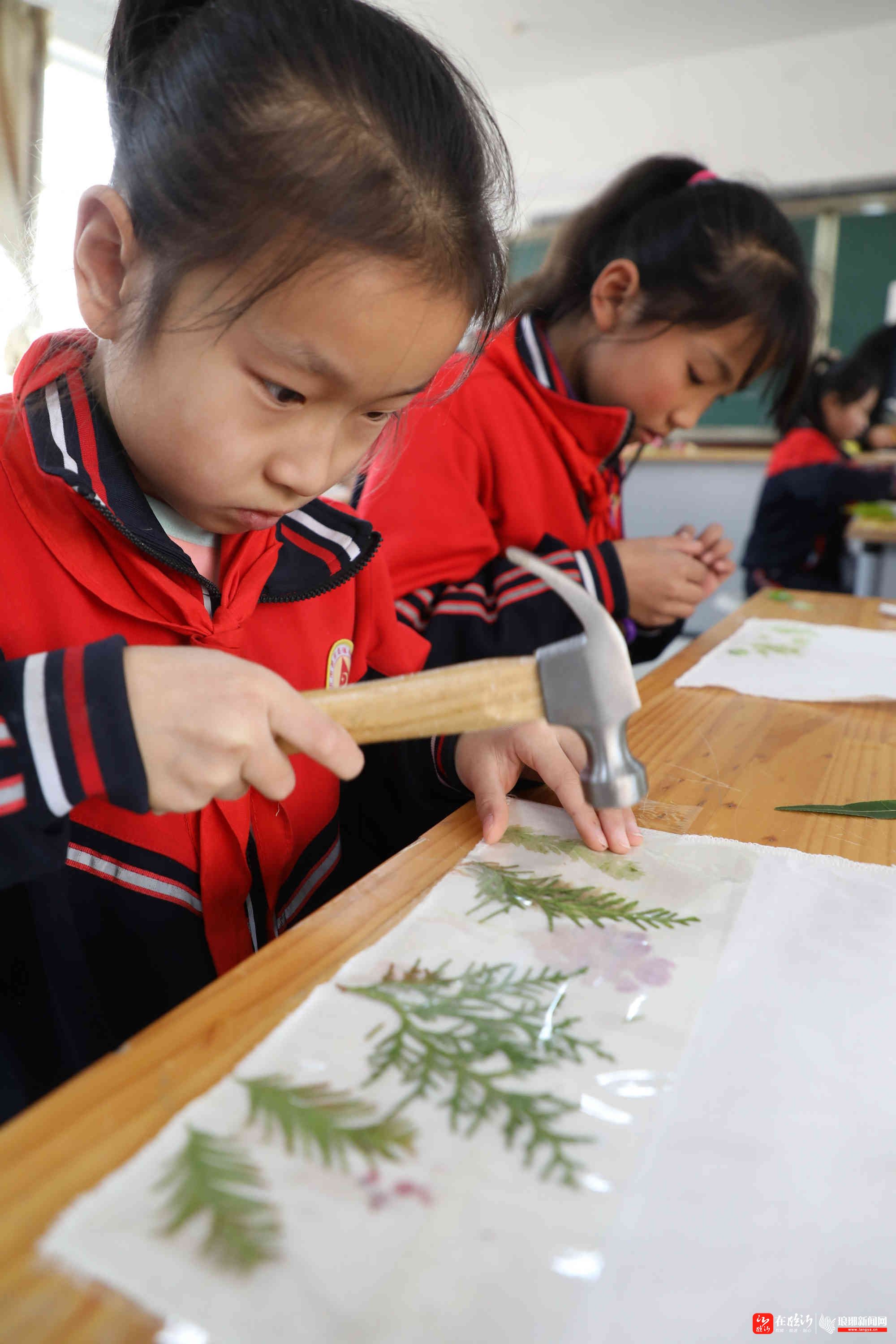 11月13日,一名小学生在展示用叶片和花瓣拓印的书包.
